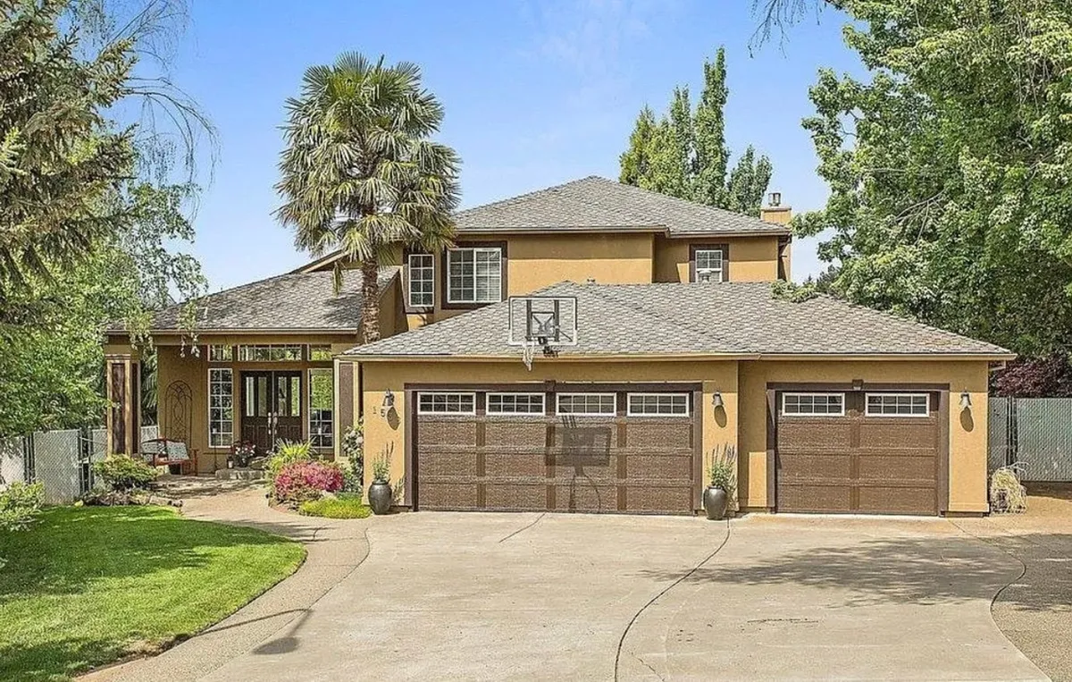 The exterior of a spacious single-family home is showcased at sunset, featuring a welcoming front porch, a basketball hoop in the driveway, and lush greenery surrounding the property. The setting evokes a sense of warmth and relaxation, inviting guests to envision outdoor play, family gatherings, and peaceful evenings in a quiet cul-de-sac.