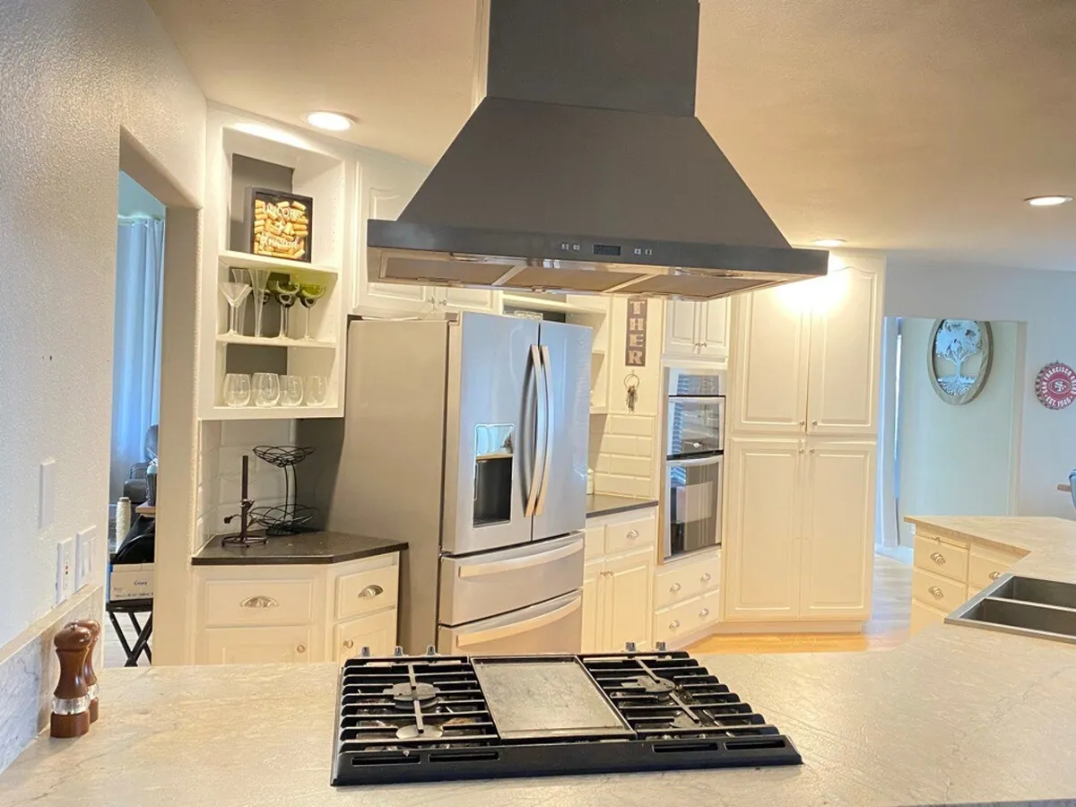 This modern kitchen features sleek stainless steel appliances, an island cooktop, and open shelving, creating a functional space for self-catering during extended business stays. The layout is open and inviting, allowing for easy meal preparation and perhaps even informal meetings or collaborative work sessions.