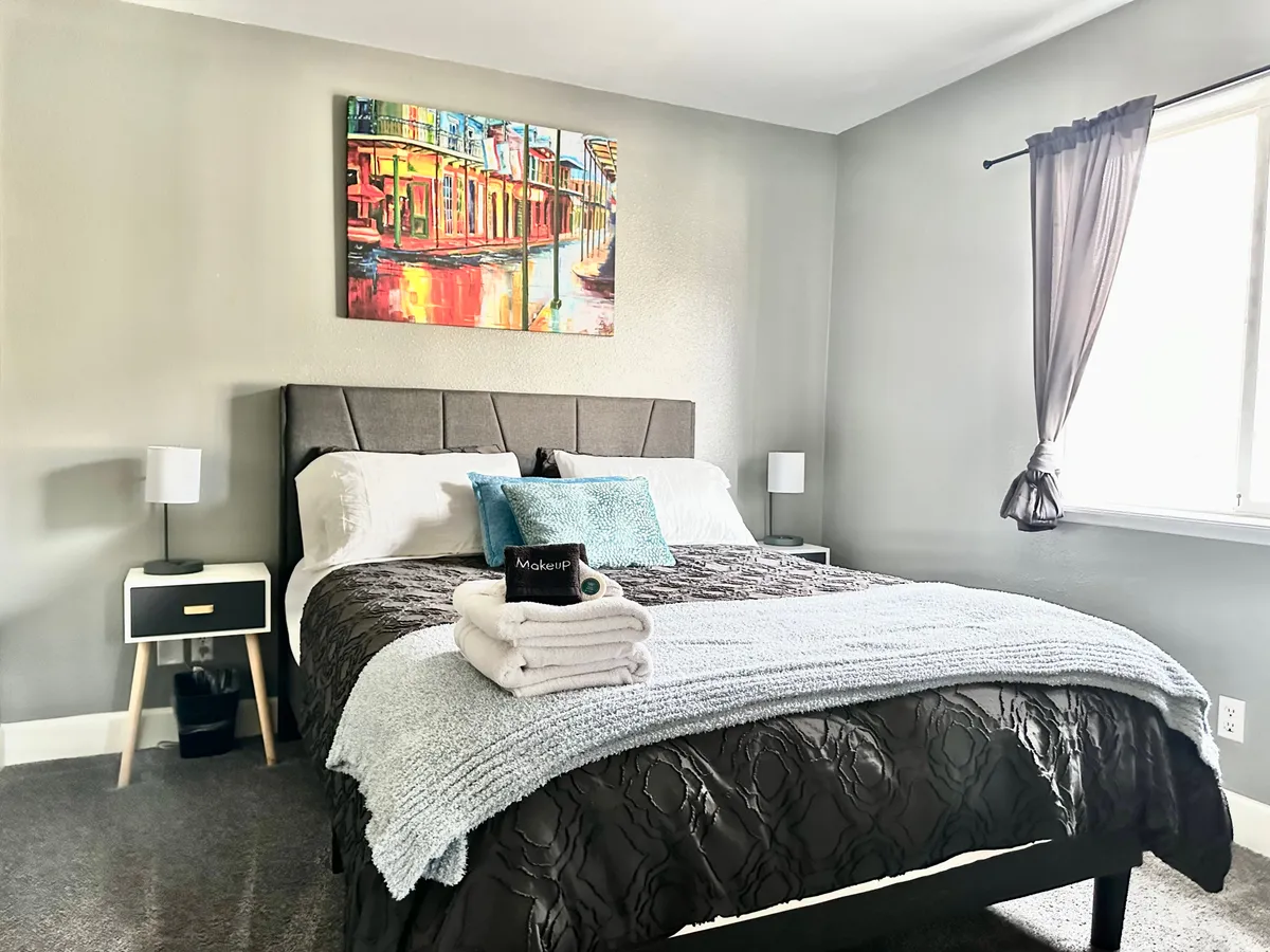 This bedroom is designed for calm, featuring a restful bed, tasteful artwork, soft bedding, and nightstands for convenience. The atmosphere is welcoming and peaceful, making it a suitable hideaway for a good night's sleep or catching up on reading in solitude.